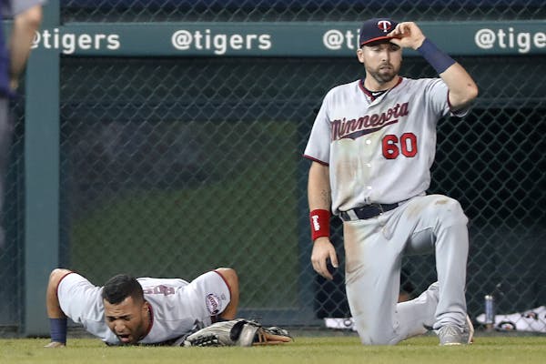 Minnesota Twins left fielder Eddie Rosario lies in left field as Jake Cave (60) waits for training staff to arrive in the fourth inning of a baseball 