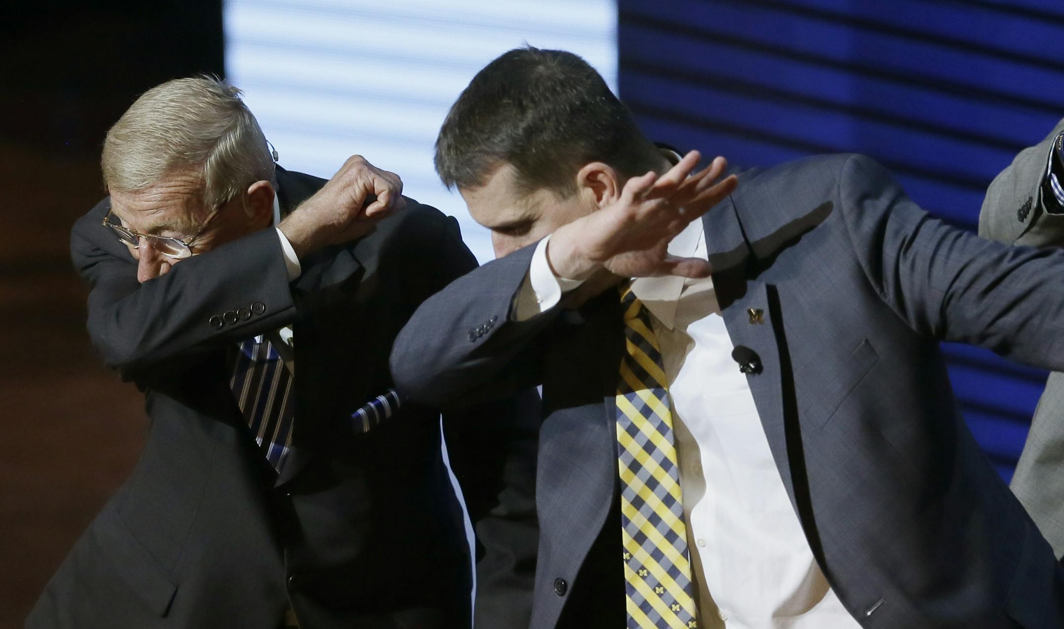 Former coach Lou Holtz, left, and University of Michigan football coach Jim Harbaugh perform a dab during the Signing With the Stars spectacle, Wednesday, Feb. 3, 2016 in Ann Arbor, Mich. Guests and superstars appeared on stage to welcome the University of Michigan's new recruits on National Signing Day. (AP Photo/Carlos Osorio)