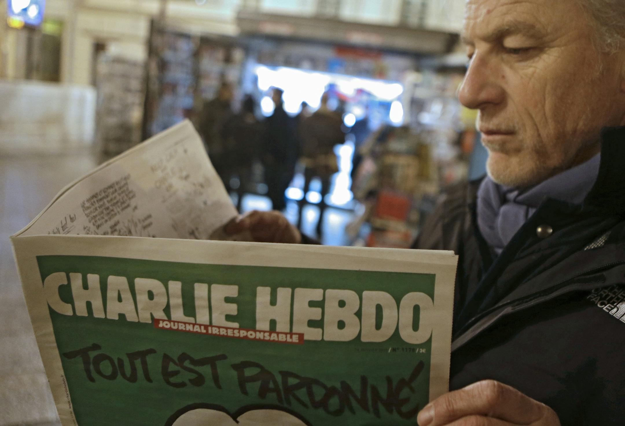 Jean Paul Bierlein reads the latest issue of Charlie Hebdo outside a newsstand in Nice, southeastern France, Wednesday, Jan. 14, 2015. In an emotional act of defiance, Charlie Hebdo resurrected its irreverent and often provocative newspaper, featuring a caricature of the Prophet Muhammad on the cover that drew immediate criticism and threats of more violence. The black letters on the front page read: "All is forgiven."