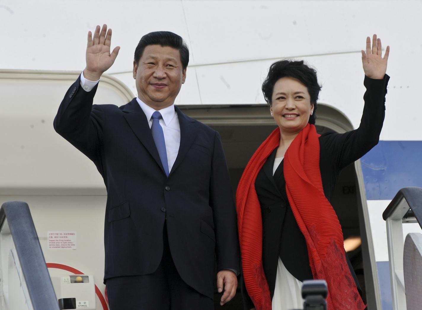 China's President Xi Jinping, left, and his wife Peng Liyuan, right, wave as they leave following a two-day official visit to the country, at the airport in Dar es Salaam, Tanzania Monday, March 25, 2013. (AP Photo/Khalfan Said)