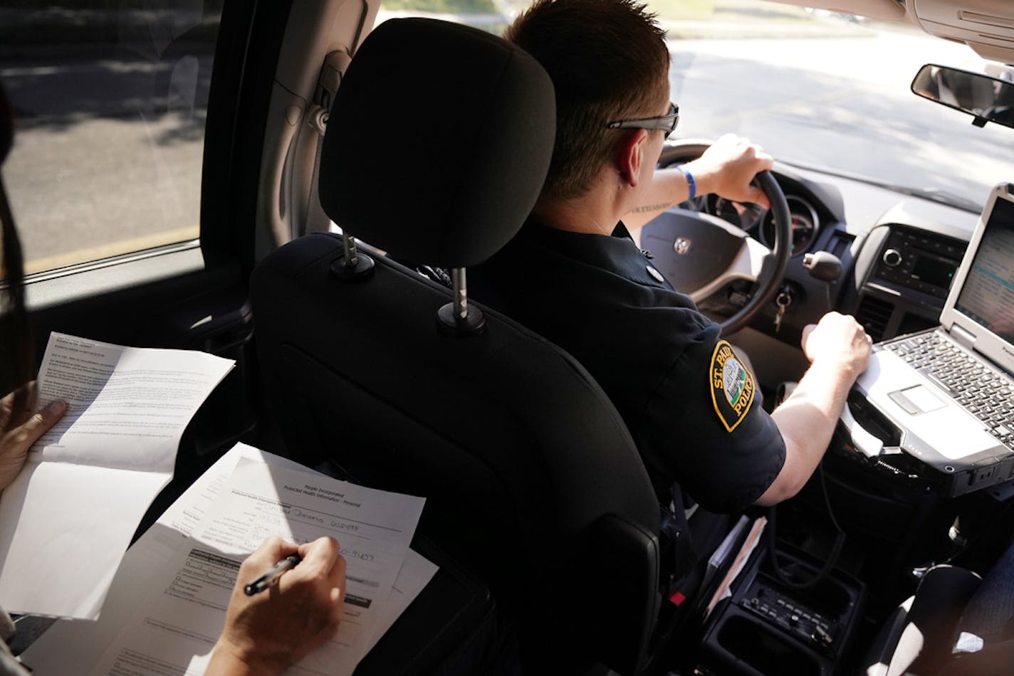 Licensed clinical social worker Amber Ruth, left, took notes on a case as officer Justin Tiffany drove them to their next call.] ANTHONY SOUFFLE • anthony.souffle@startribune.com