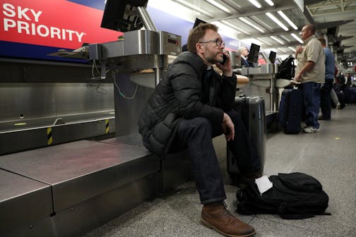 Nick Wilson of Hampshire, England waited to speak to a travel agent to reschedule his flight back to London after his first flight though Chicago was cancelled yesterday and MSP grounded all flights due to the snow today.