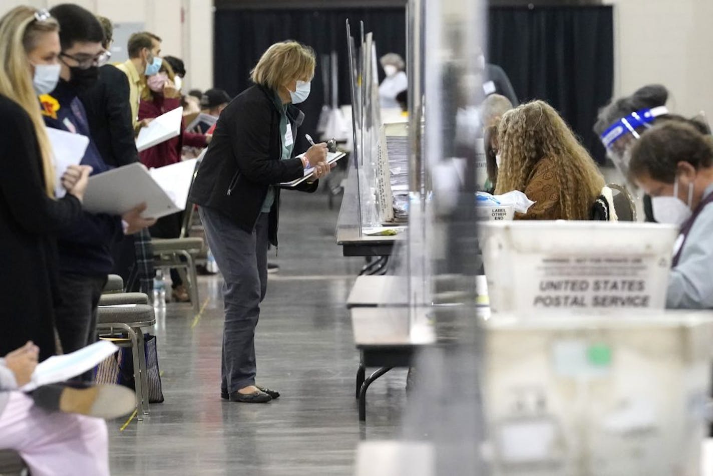 Recount observers watch ballots during a Milwaukee hand recount of Presidential votes at the Wisconsin Center, Friday, Nov. 20, 2020, in Milwaukee, Wis. The recount of the presidential election in Wisconsin's two most heavily Democratic counties began Friday with President Donald Trump's campaign seeking to discard tens of thousands of absentee ballots that it alleged should not have been counted.