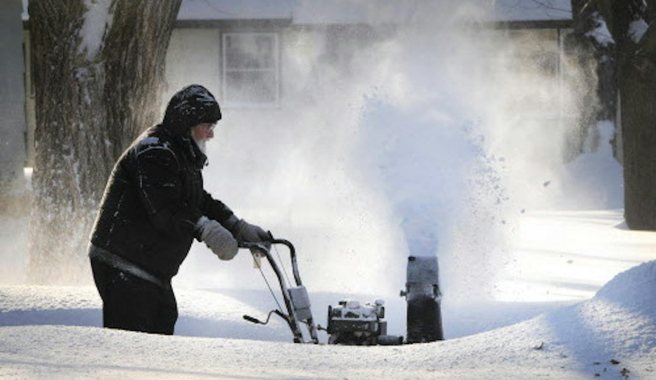 Walter Berg cleans about six inches of new-fallen snow from his driveway in St. Cloud, Minn., Saturday morning, Jan. 18, 2014. (AP Photo/The St. Cloud Times, Dave Schwarz)