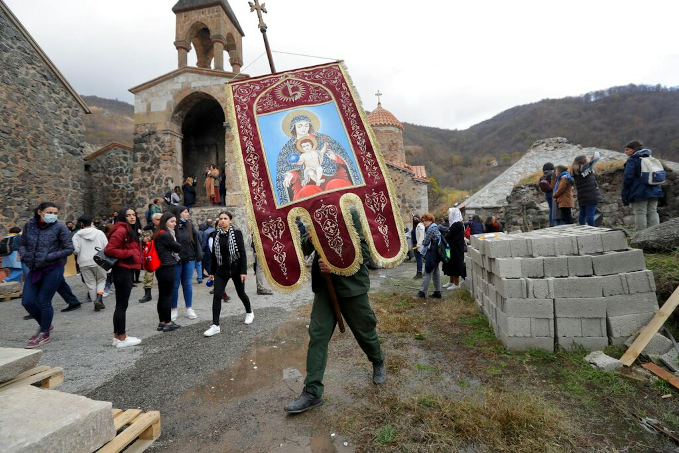 A church worker carry gonfalons out from the 12th-13th century Orthodox Dadivank Monastery on the outskirts of Kalbajar, the separatist region of Nagorno-Karabakh, on Friday, Nov. 13, 2020. Under an agreement ending weeks of intense fighting over Nagorno-Karabakh, some Armenian-held territories, such as this area, will pass to Azerbaijan. (AP Photo/Sergei Grits)