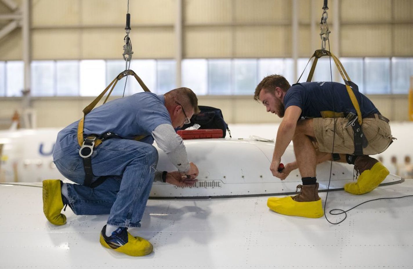 Bradley Gangstad, left, a mechanic at AAR Corp., and Kieran Cummings worked to attach a dome protecting radar equipment on top of a commercial airplane in Duluth.