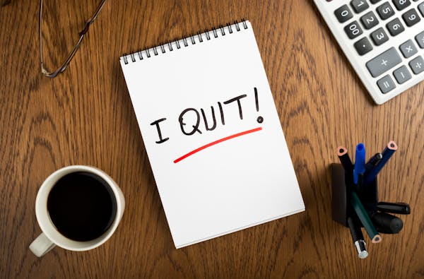 spiral note pad with "I quit!" message on the office desk.