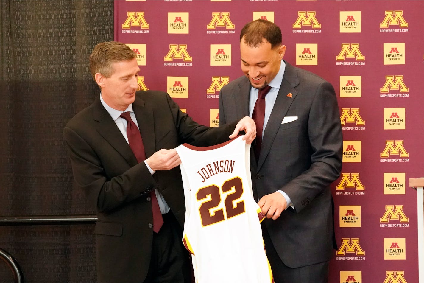 New University of Minnesota mens' head basketball coach Ben Johnson, right, receives his own number from athletic director Mark Coyle following a press conference to introduce Johnson, Tuesday, March 23, 2021, in Minneapolis. Johnson replaces Richard Pitino, who was fired after eight seasons and took the job at New Mexico. (AP Photo/Jim Mone)