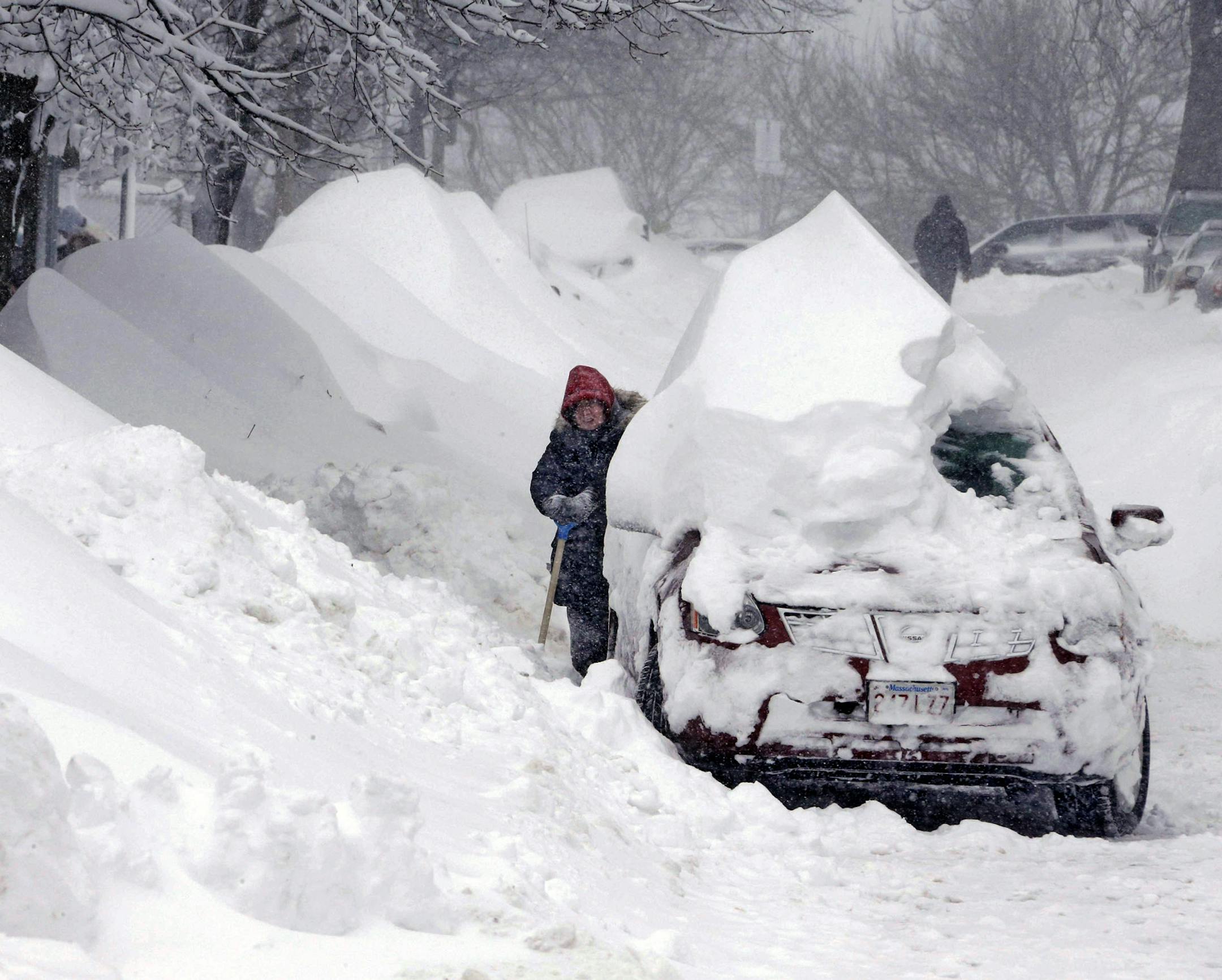 A woman shovels snow to clear out a car on Third Street in the South Boston neighborhood of Boston on Saturday, Feb. 9, 2013. A behemoth storm packing hurricane-force wind gusts and blizzard conditions swept through the Northeast overnight. ORG XMIT: MIN2013020920070508