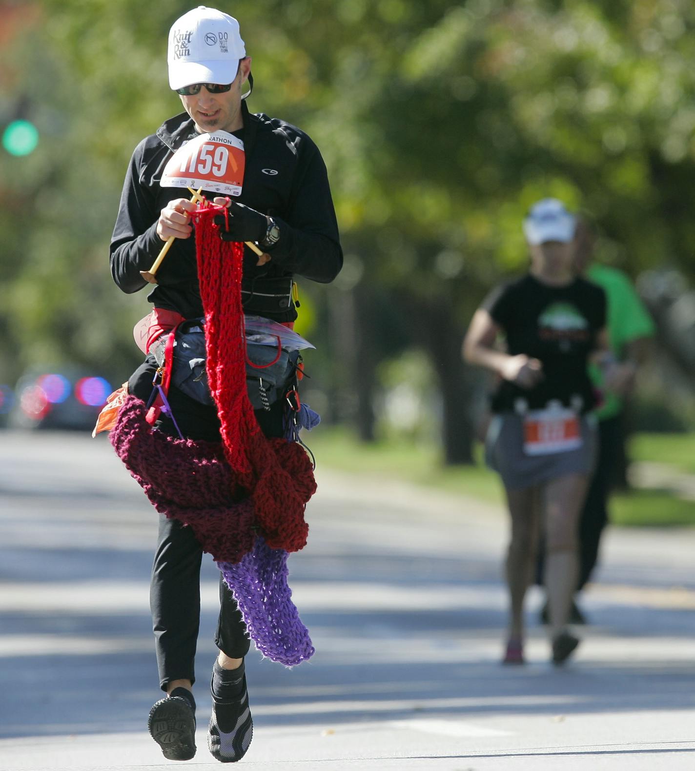 David Babcock knits a scarf along Brookside Boulevard and the rest of the 26.2 mile run in Kansas City, Mo., Saturday, Oct. 19, 2013. Babcock finished the marathon in 5 hours, 48 minutes and 27 seconds. Knitting experts measured the scarf he created along the route at just more than 12 feet long. (AP Photo/The Kansas City Star, Jim Barcus)