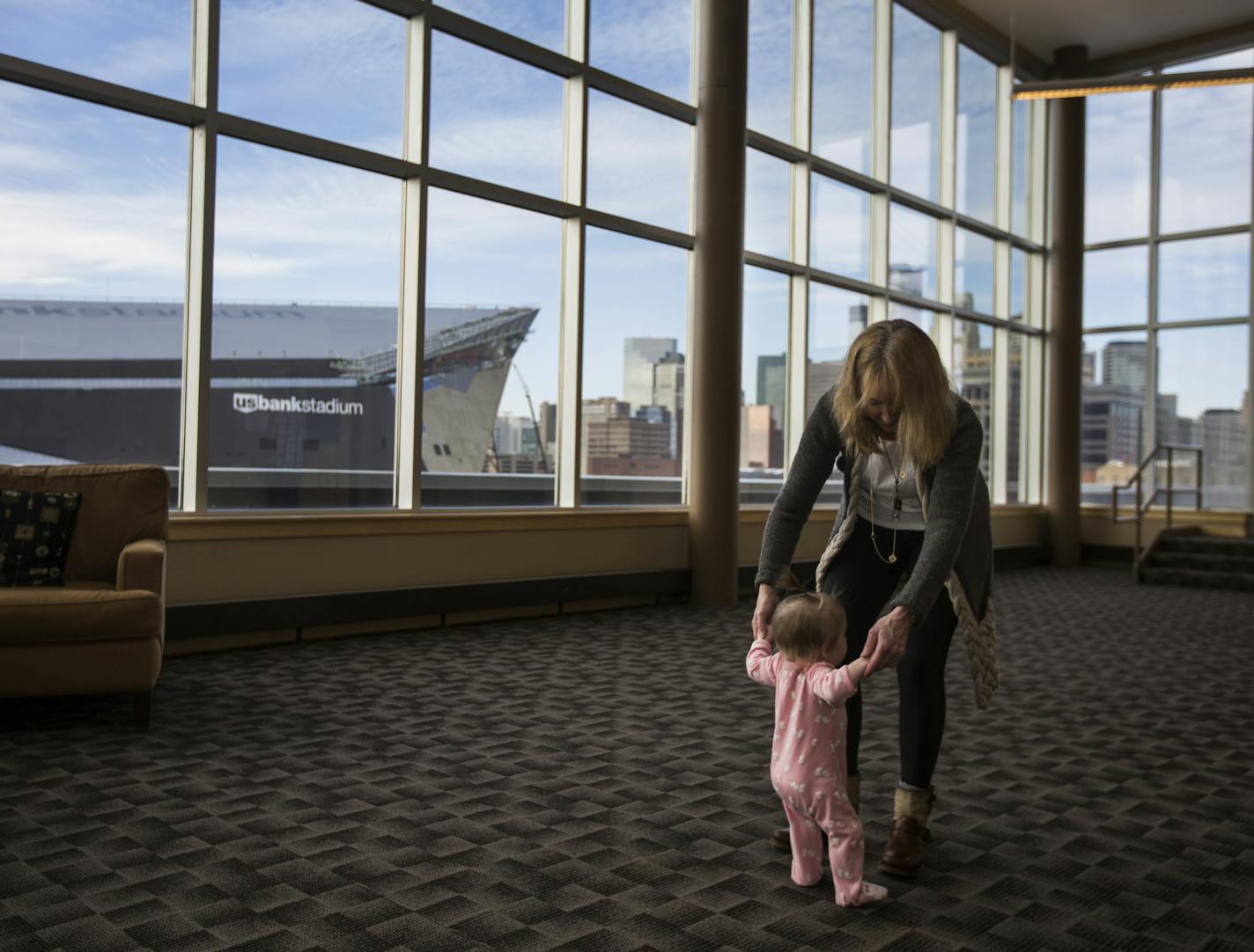 Paula van De Laarschot let her granddaughter Cameron van De Laarschot practice walking around in the community room Bridgewater Lofts with a view of the U.S. Bank Stadium on Friday, January 29, 2016 in Minneapolis, Minn. ] RENEE JONES SCHNEIDER &#x2022; reneejones@startribune.com