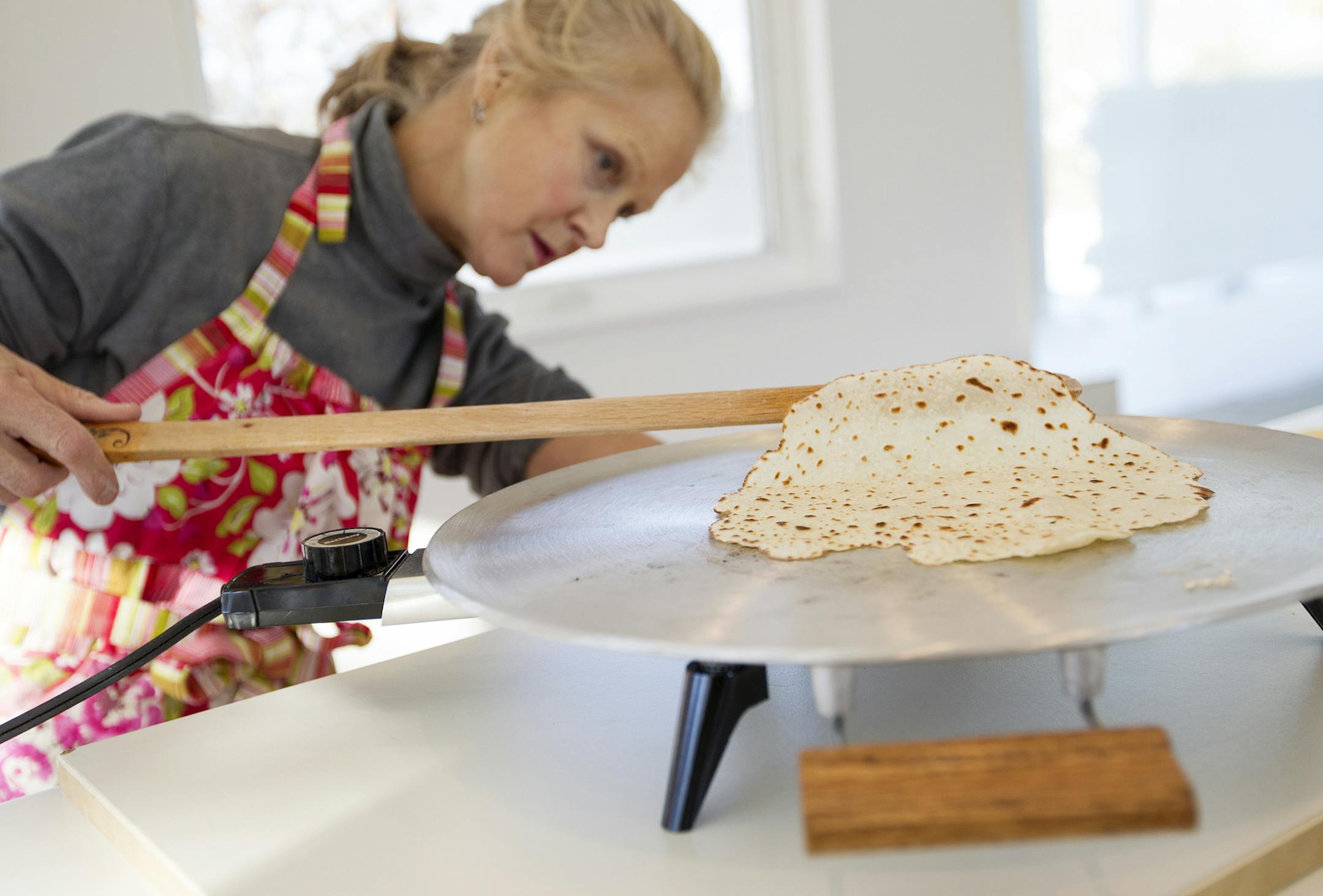 Kathy Kvammen-McKinley checks her lefse on the griddle as women in the Circle of Gratitude group from Minneapolis' Central Lutheran Church make hundreds of lefse for a Scandinavian Bake Sale at the home of Rebecca Jorgenson Sundquist in Deephaven December 6, 2013. (Courtney Perry/Special to the Star Tribune)