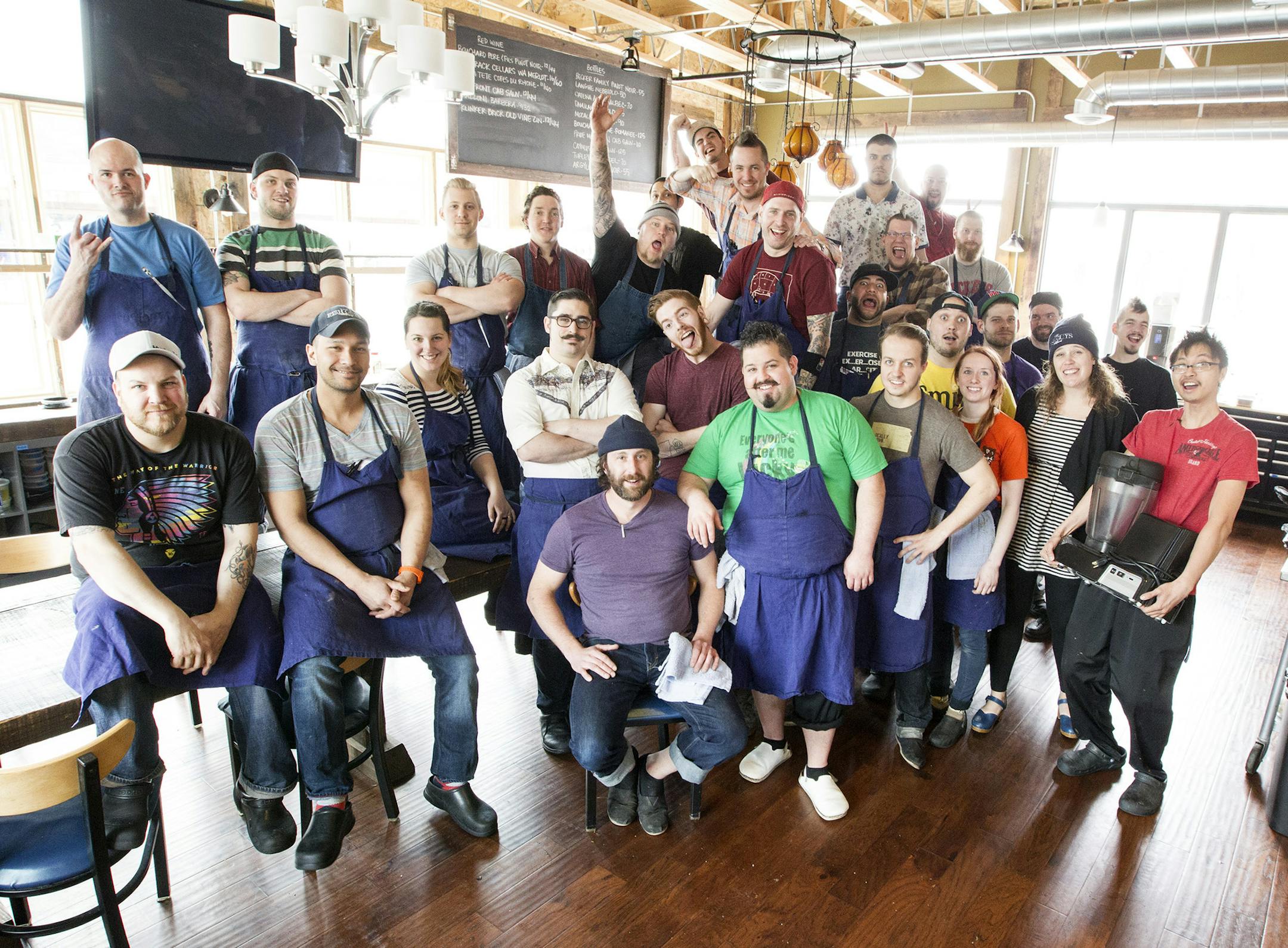 Owners Mike Brown, front center (green shirt), James Winberg, seated next to Brown, and Bob Gerken, second from left in front row, stand with their staff at Travail and the Rookery in Robbinsdale April 18, 2014. (Courtney Perry/Special to the Star Tribune)