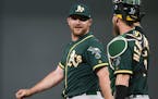 Oakland Athletics pitcher Liam Hendriks, left, celebrates with catcher Chris Hermann after the Athletics defeated the Minnesota Twins 5-3 in a basebal