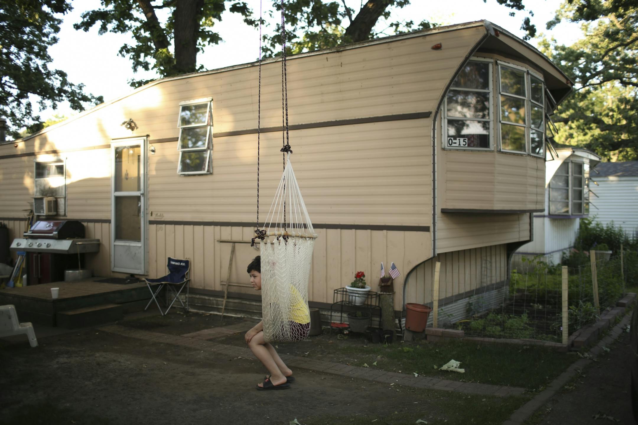 Edwin Morales sat in a chair suspended from a tree outside the mobile home he lives in at Lowry Grove.