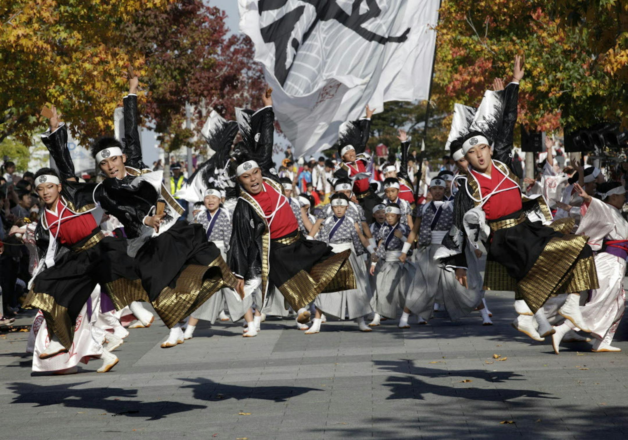 Participants jump as they dance through a street during the annual "Yosakoi" festival in Tokyo Sunday, Nov. 1, 2015. Yosakoi is a unique and modern rendition of the popular traditional Japanese dance of Awa Odori and many troupes compete with their choreographed dance in colorful costumes, performed often with the Japanese instrument of Naruko, a clapper held in both hands. (AP Photo/Shizuo Kambayashi)