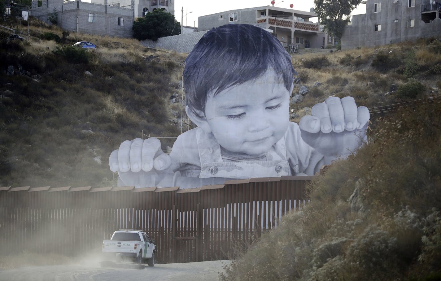 A Border Patrol vehicle drove in front of a mural in Tecate, Mexico, just beyond a barrier on the United States side. Associated Press