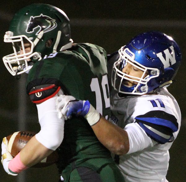 Nico Bolden of Woodury, #11 (right), making a tackle in a game against Mounds View.