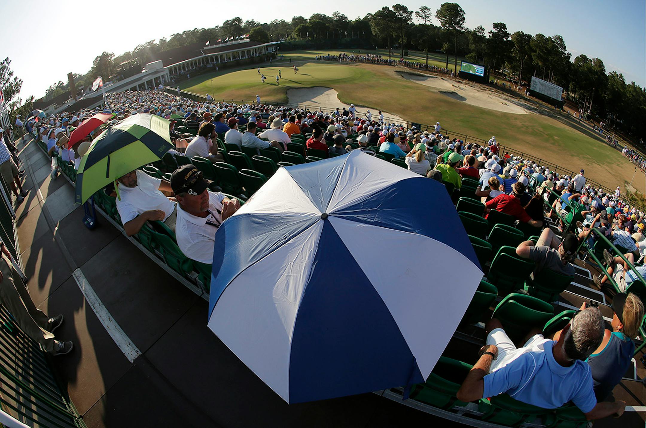 In this image made with a fish eye lens, Fans watch as Dustin Johnson arrives at the 18th hole during the third round of the U.S. Open golf tournament in Pinehurst, N.C., Saturday, June 14, 2014.
