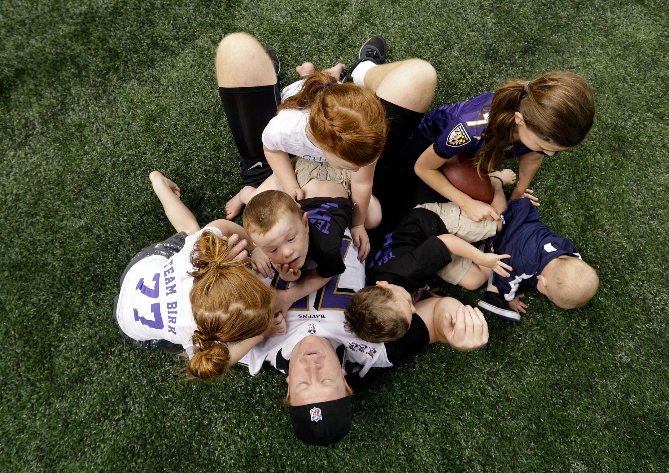 Baltimore Ravens center Matt Birk, bottom, plays with his children on the Mercedes-Benz Superdome field after an NFL Super Bowl XLVII walkthrough on Saturday, Feb. 2, 2013, in New Orleans. The Ravens face the San Francisco 49ers in Super Bowl XLVII on Sunday. (AP Photo/Patrick Semansky)