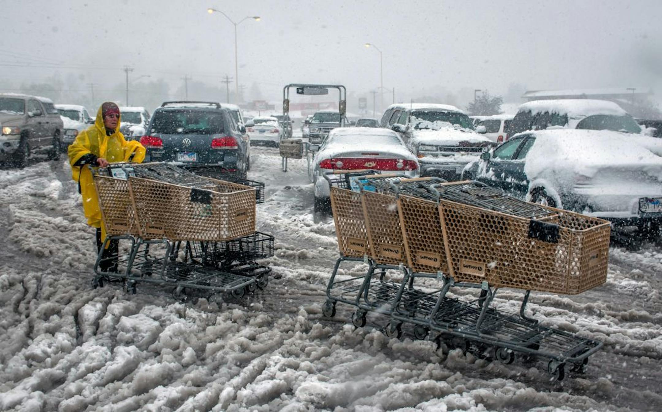 Mari Havens, a courtesy clerk at a Rapid City, S.D. Safeway store, gathers up shopping carts in the store's wind and snow swept parking lot Friday, Oct. 4, 2013. Blizzards rolled into parts of Wyoming and South Dakota on Friday, bringing the snow-savvy states to an unseasonably early winter standstill.