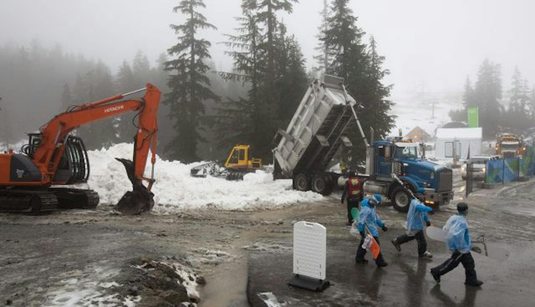 Work crews continue to move snow as heavy rain falls prior to the start of the men's and women's mogul training for the 2010 Vancouver Olympic Winter Games at Cypress Mountain in Vancouver, British Columbia Thursday Feb. 11, 2010.