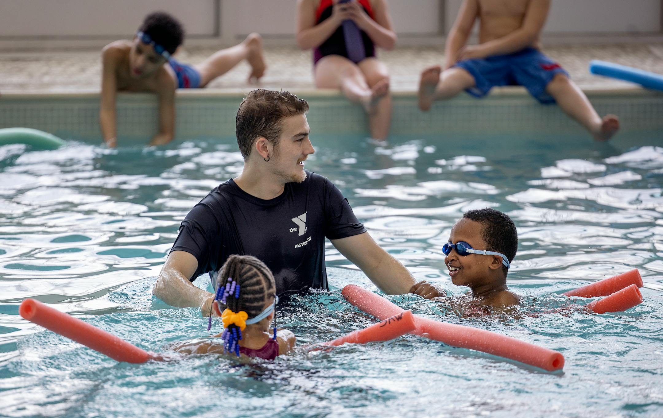 Sam Austin, a St. Cloud YMCA swim instructor, teaches   Madison Elementary second-graders how to swim with pool noodles.