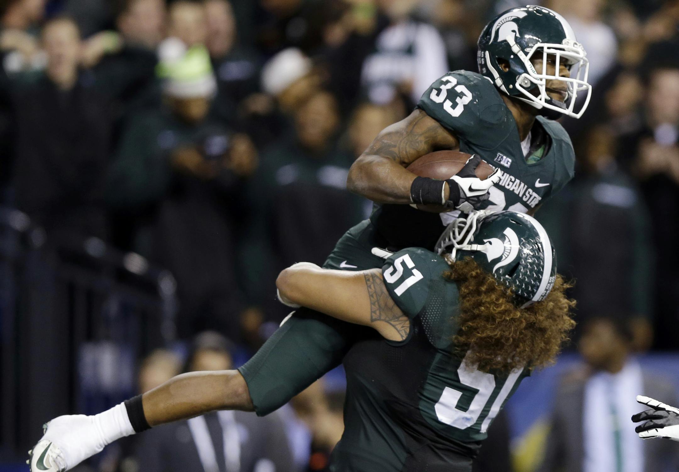 Michigan State's Jeremy Langford (33) celebrates with Fou Fonoti (51) after Langford ran 26-yards for a touchdown during the fourth quarter of an Big Ten Conference championship NCAA college football game against Ohio State, Saturday, Dec. 7, 2013, in Indianapolis. (AP Photo/Michael Conroy)