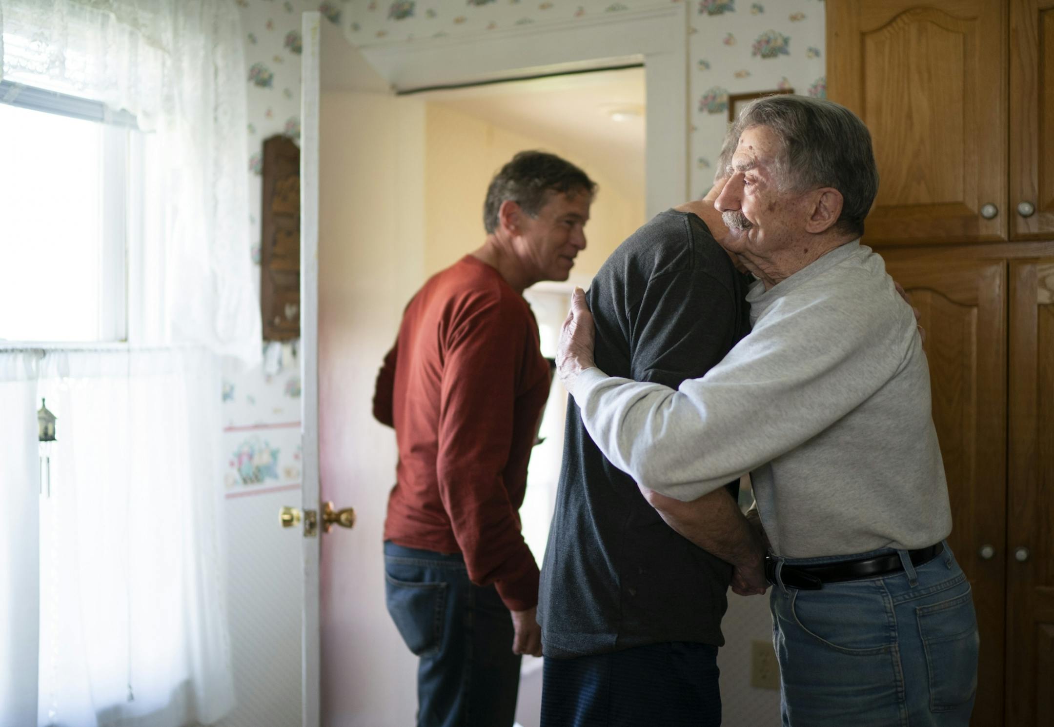 After most morning hockey games, buddies come over to Mark Sertich's house for coffee and conversation. Sertich hugged Bob Somers after he and Dane Youngblom, left, stopped by after Thursday morning's game.