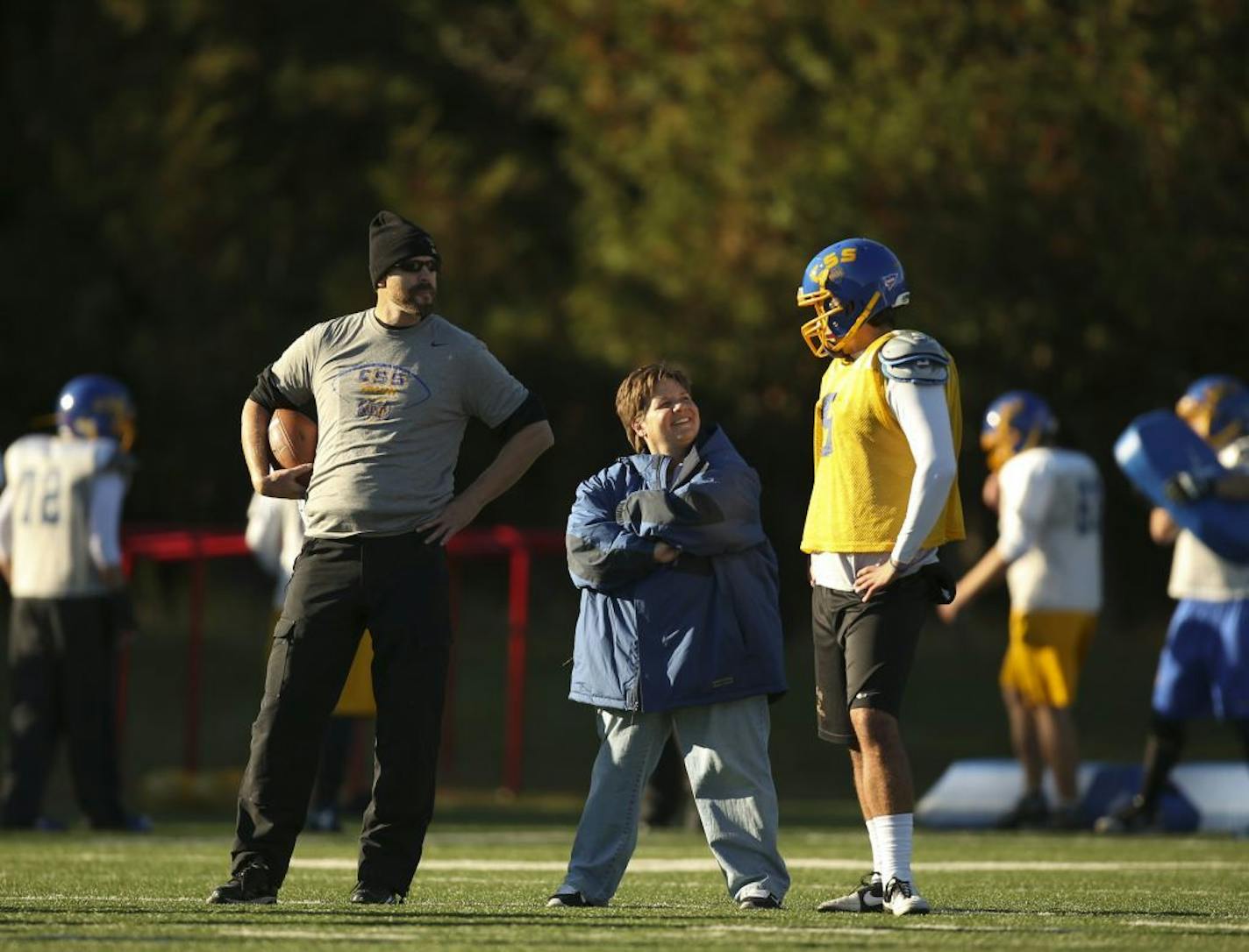 Head coach Kurt Ramler stood with kickers and punters coach Sister Lisa Mauer and kicker Mike Theismann while they watched a punter take snaps during practice earlier this month.