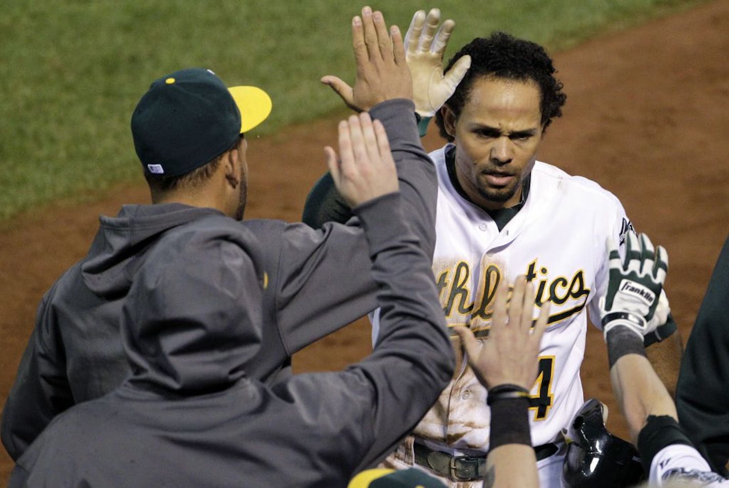 Oakland Athletics' Coco Crisp celebrates in the dugout after scoring on a double by Stephen Drew in the sixth inning of Game 4 of their American League division baseball series against the Detroit Tigers in Oakland, Calif., Wednesday, Oct. 10, 2012.