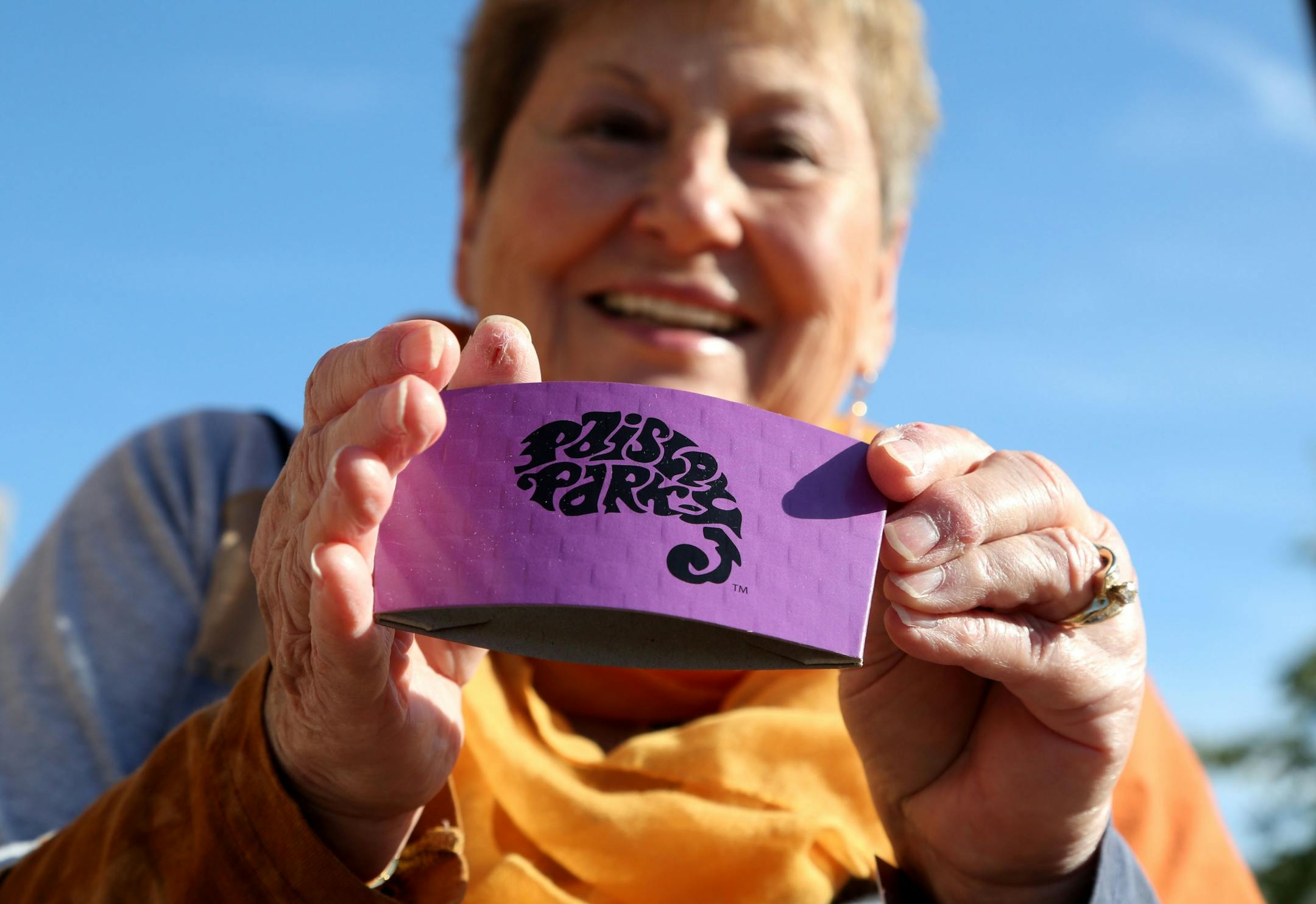 Phyllis Jackson of Red Wing didn't buy any coffee during the Paisley Park tour but she did pick up a coffee sleeve for free and showed it off at Southwest Transit Center where tour guests were picked up and dropped off for the tour Thursday, Oct. 6, 2016, in Chanhassen, MN.