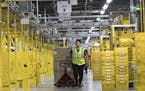 In this Wednesday, Dec. 5, 2018, photo an employee moves merchandise in Amazon fulfillment center on Staten Island borough of New York. (AP Photo/Mary