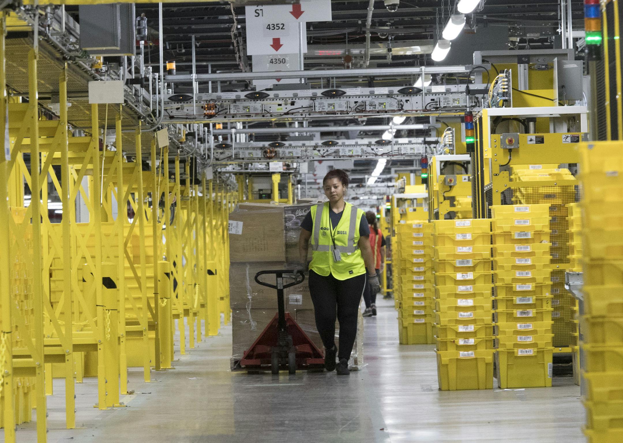 In this Wednesday, Dec. 5, 2018, photo an employee moves merchandise in Amazon fulfillment center on Staten Island borough of New York. (AP Photo/Mary Altaffer) ORG XMIT: NYMA209