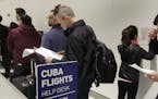 Passengers look over their paperwork while waiting to check in for JetBlue's inaugural flight from New York's John F. Kennedy International Airport to