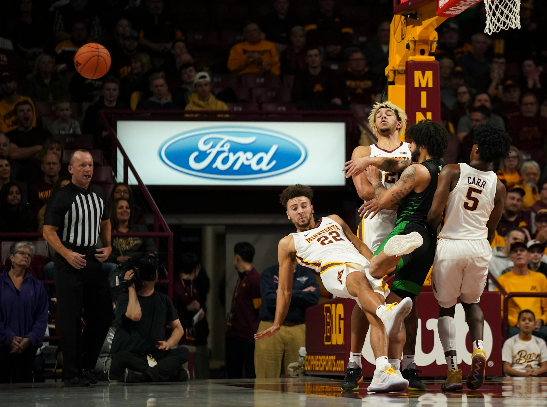 North Dakota guard Marlon Stewart (1) plowed into Minnesota's Gabe Kalscheur (22), Jarvis Omersa (21) and Marcus Carr (5) on Sunday during the first half.