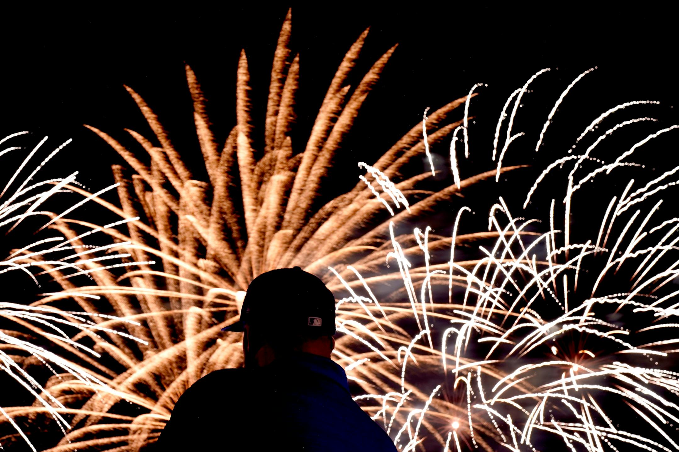 A member of the Kansas City Royals grounds crew watches a Fourth of July fireworks display after a baseball game against the Minnesota Twins Friday, July 2, 2021, in Kansas City, Mo. The Royals won 7-4. (AP Photo/Charlie Riedel)