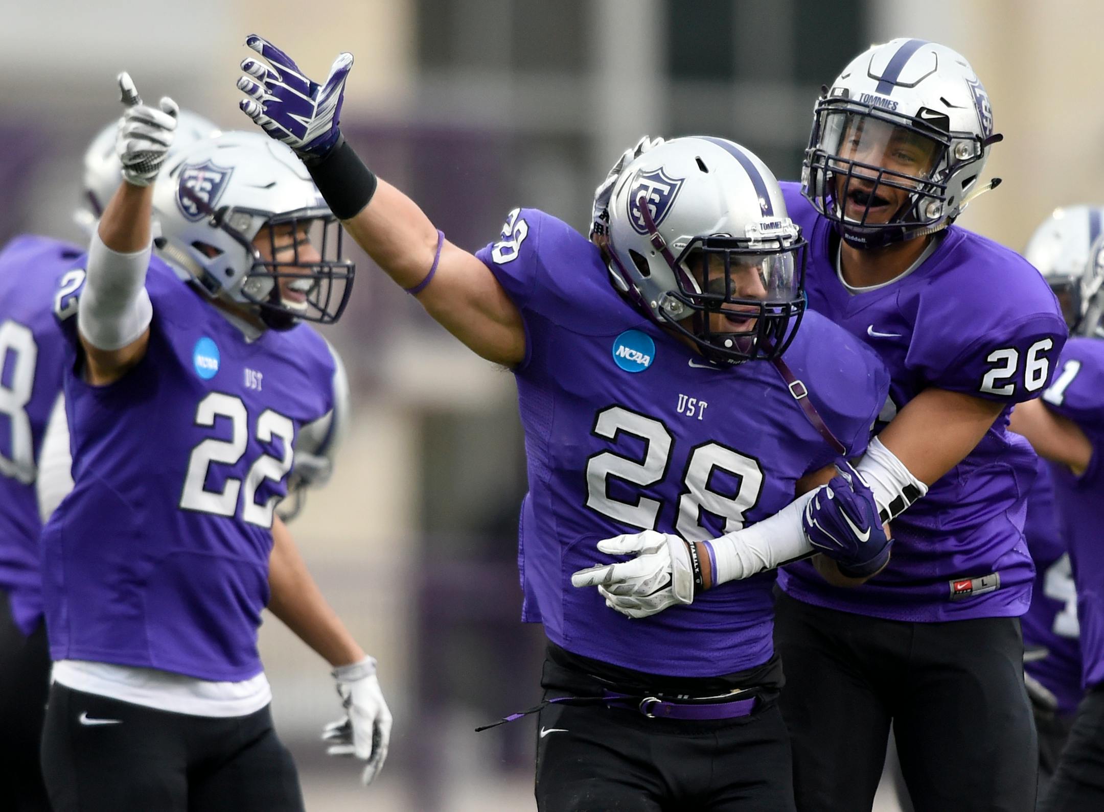 St. Thomas defensive back Jordan Young (22), linebacker Steve Harrell (28) and linebacker Alex Stevson (26) celebrate a fumble recovery by Harrell against the Linfield during the first quarter of a Division III NCAA college football semifinal game on Saturday, Dec. 12, 2015, in St. Paul, Minn. (AP Photo/Hannah Foslien)