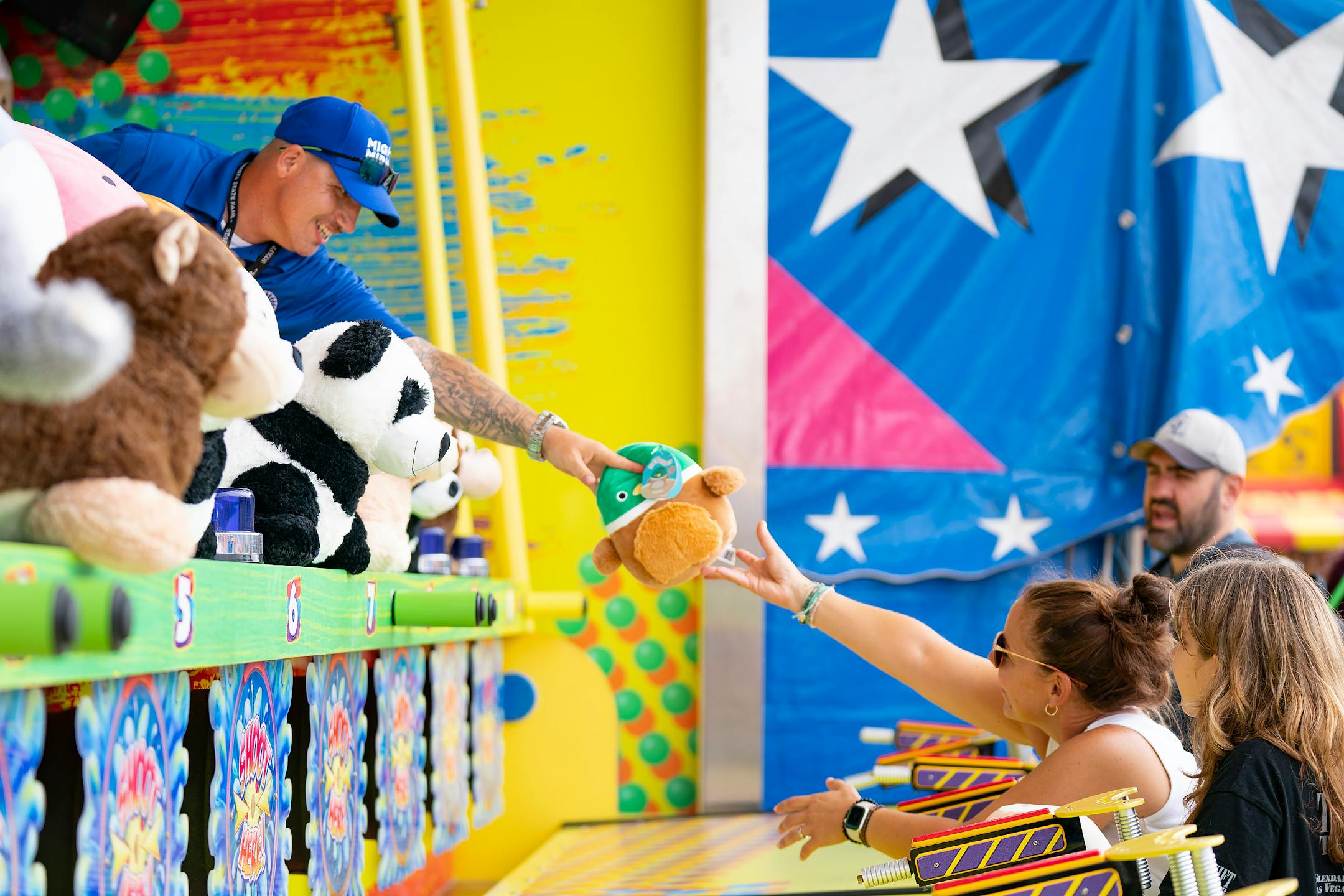 A game operator hands Lindsey Clayton-King a prize after she won a water squirter game.