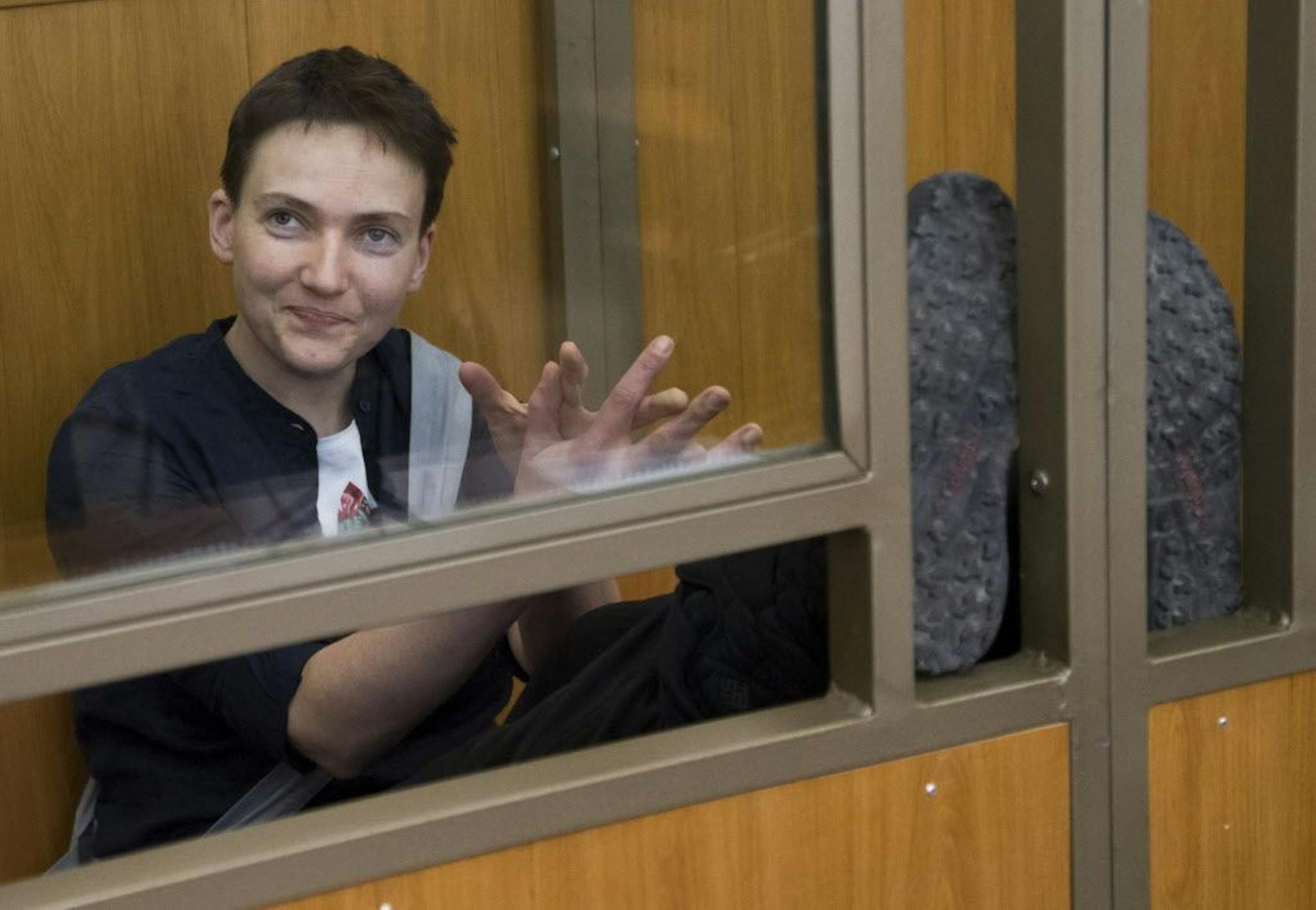 Ukrainian pilot Nadezhda Savchenko applauds and smiles in a glass cage inside court, in the town of Donetsk, Rostov-on-Don region, Russia, Tuesday, March 22, 2016, as she awaited her verdict.