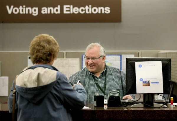 Hennepin County Voting and Elections Office Specialist Andrew Krueger helped voter Mary Ellen Gallick with her ballot at the absentee-voting polls at 