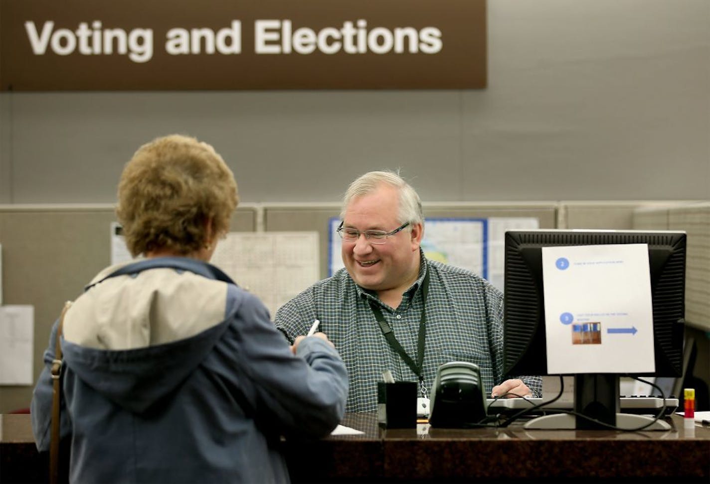 Hennepin County Voting and Elections Office Specialist Andrew Krueger helped voter Mary Ellen Gallick with her ballot at the absentee-voting polls at the Hennepin County Government Center, Thursday, October 23, 2014 in Minneapolis, MN.