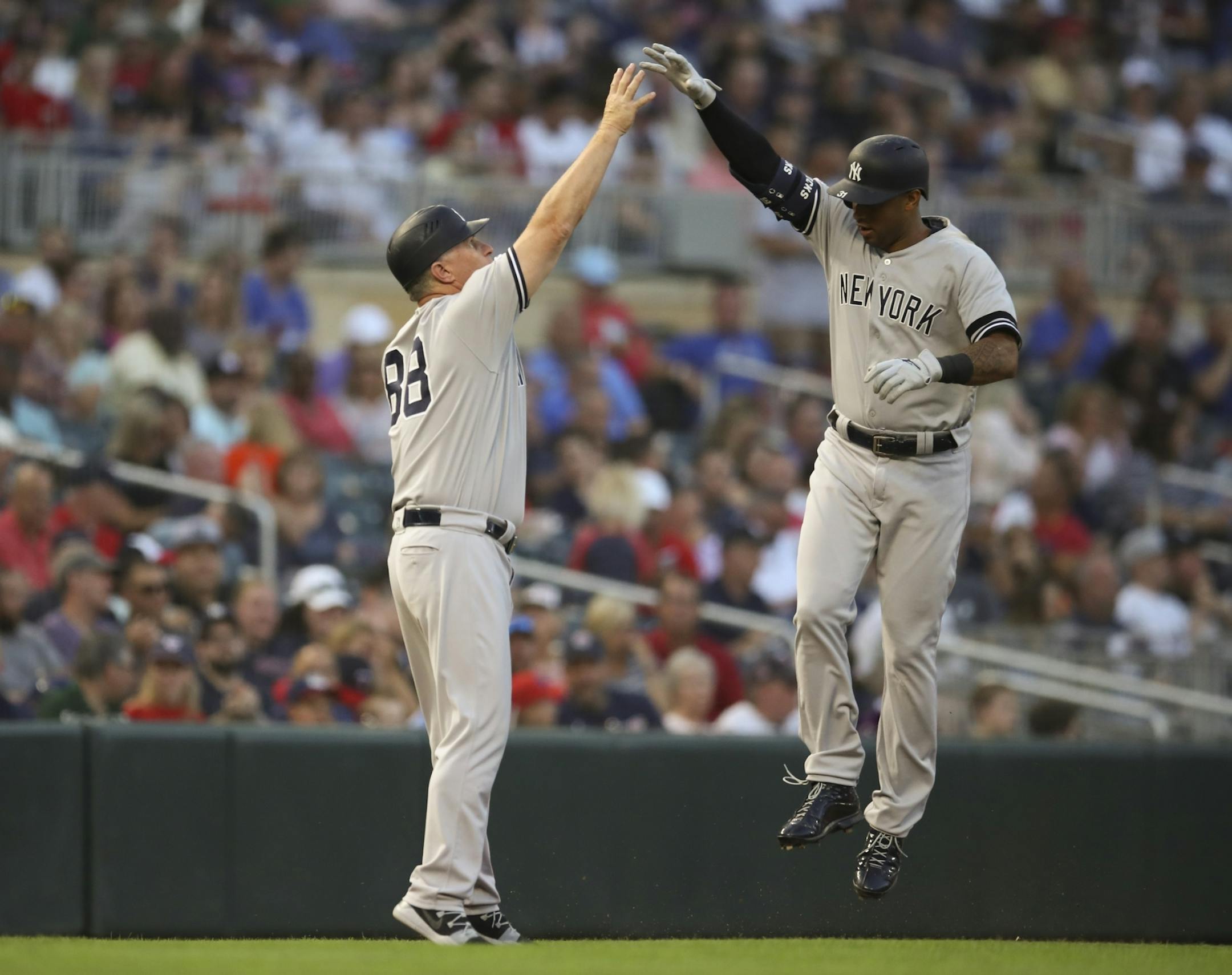 New York Yankees center fielder Aaron Hicks high fived third base coach Phil Nevin (88) after his third inning solo homer off Jake Odorizzi.