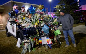 Savage police Sgt. Jacob Swartout bumped his fist against a fallen officer's squad car Tuesday. Two officers and a paramedic were killed Sunday during