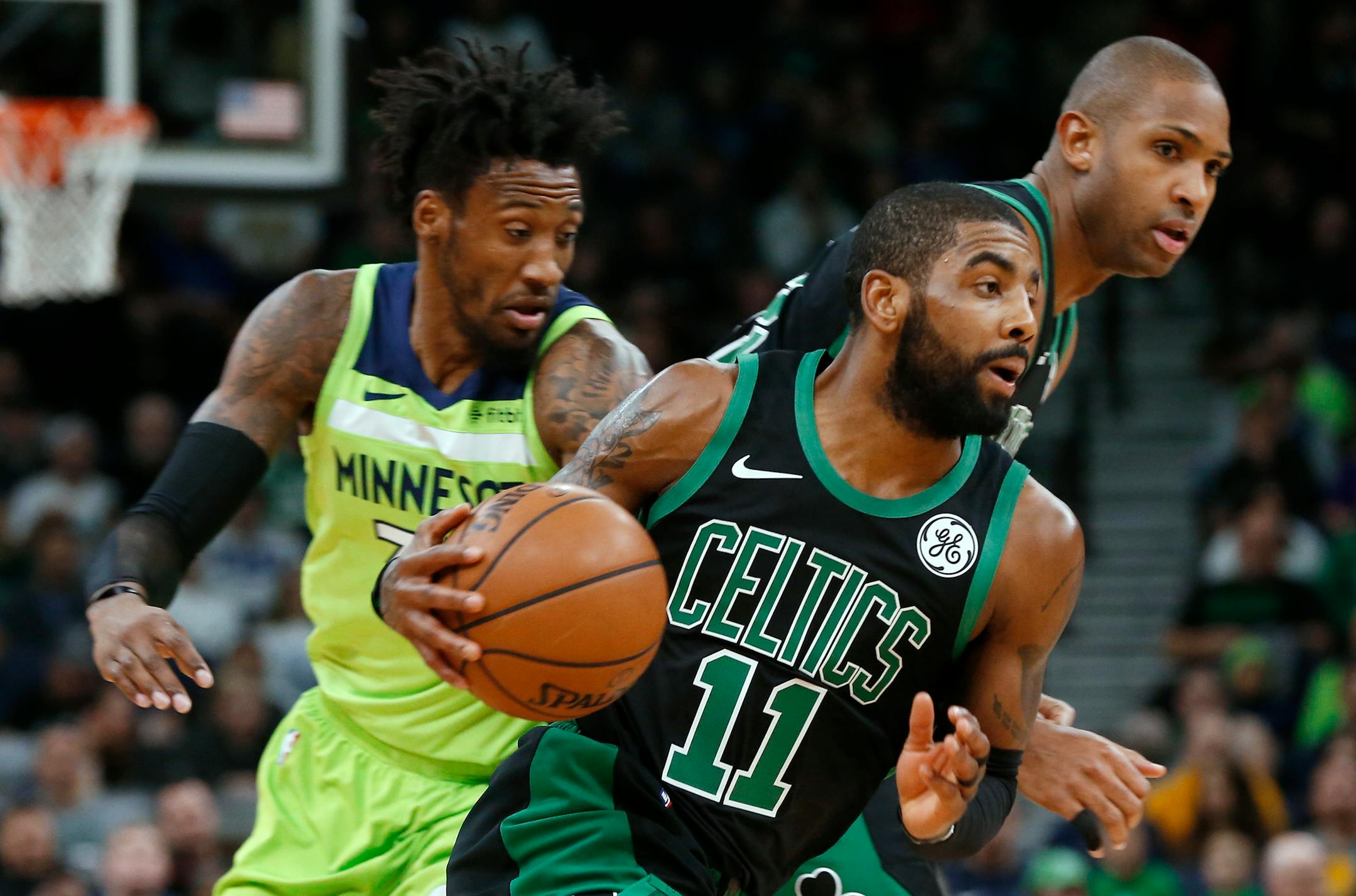Boston Celtics' Kyrie Irving, center, drives as Minnesota Timberwolves' Robert Covington, left, pursues