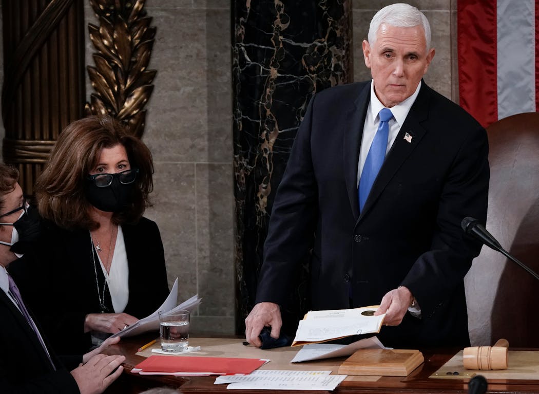 Vice President Mike Pence stood to officiate with Speaker of the House Nancy Pelosi, D-Calif., as a joint session of the House and Senate convenes to count the Electoral College votes cast in November's election, at the Capitol in Washington, Jan. 6, 2021.