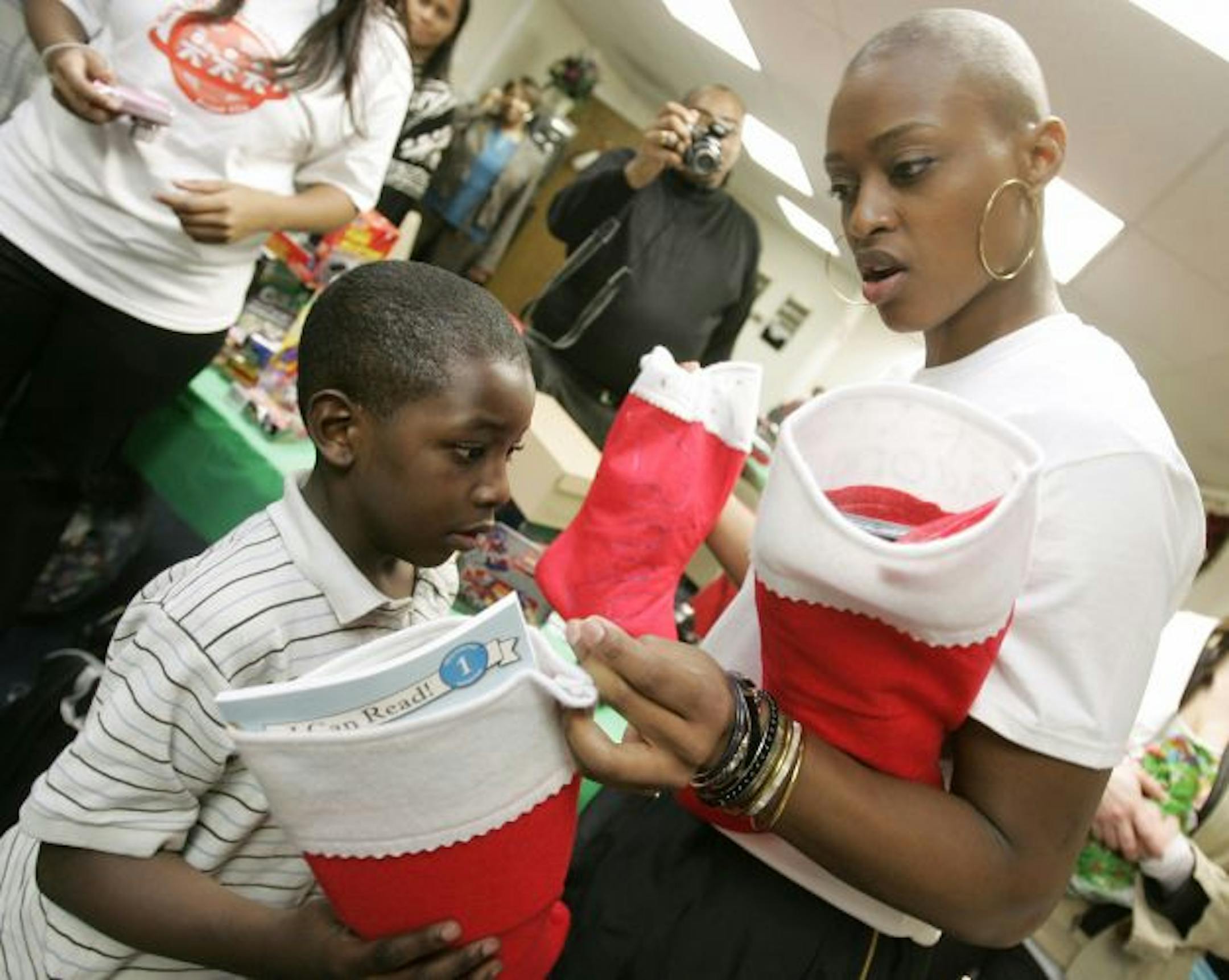 SPECIAL TO MINNEAPOLIS STAR TRIBUNE-- Charde Houston, right, a basketball player with the Minnesota Lynx of the WNBA, distributes Christmas presents to the Deamondre Scott, 7, his mother and four brothers and sisters at the Youth Advocate Program office in Atlantic City, N.J. on Wednesday, Dec. 22, 2010. Houston's foundation, Project Youth Opportunities Unlimited, raised the money in conjunction with the Youth Advocate Program of Atlantic County. The gifts included, clothing, an I Pod, laptop co