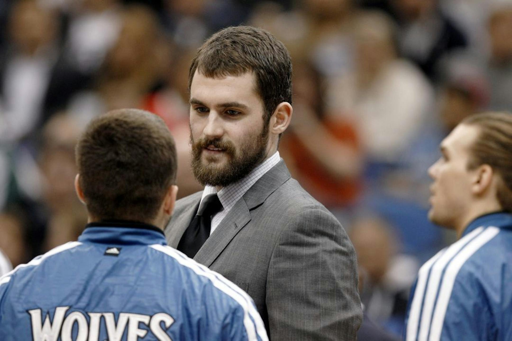 Injured Minnesota Timberwolves forward Kevin Love talks to teammates.