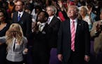 Republican presidential candidate Donald Trump, right, stands and listens during a church service at Great Faith Ministries, Saturday, Sept. 3, 2016, 