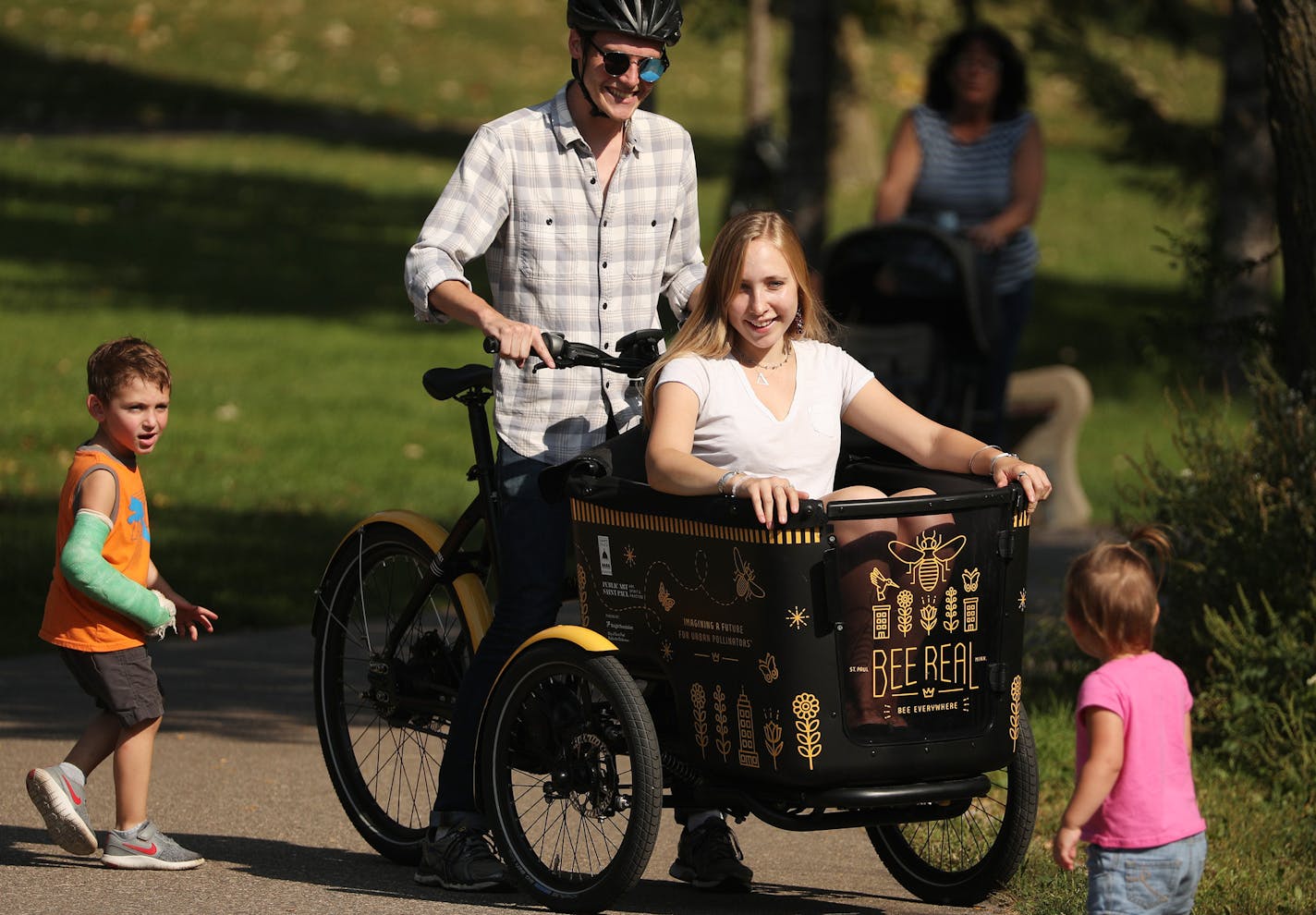 Luke Myers and Hannah Whitney, education assistants with Bee Real Bee Everywhere rode around on the electric bike they've dubbed the "beemobile" following the unveiling the city's first bee "Sky-Rise" habitat. ] ANTHONY SOUFFLE &#xef; anthony.souffle@startribune.com Public Art St. Paul held a event to unveil the city's first bee "Sky-Rise" habitat Wednesday, Sept. 13, 2017 near Como Park in St. Paul, Minn. The high rise home for pollinators was designed to not only provide bee habitat, but to al